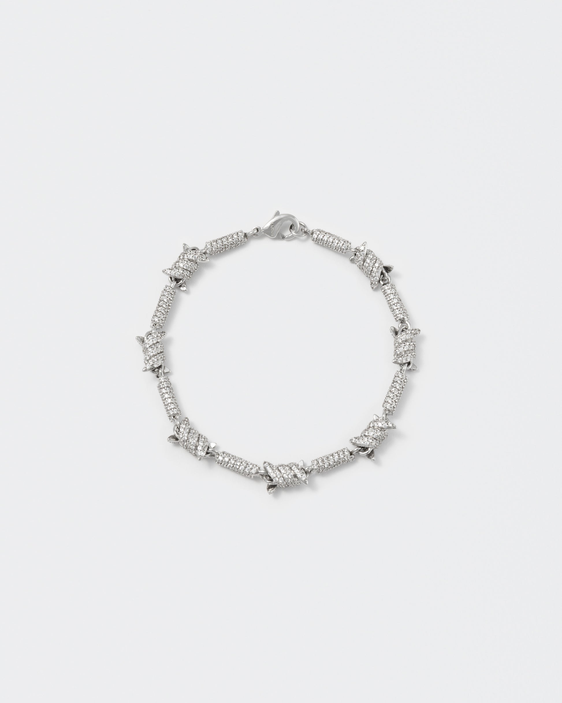 Barbed Wire bracelet with 18kt white gold coating and hand-set micropavé stones in diamond white. Lobster clasp closure with logo